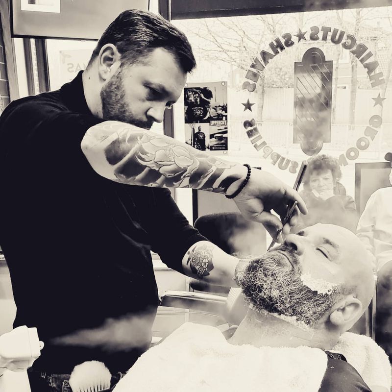 Dean shaping a beard with an open razor